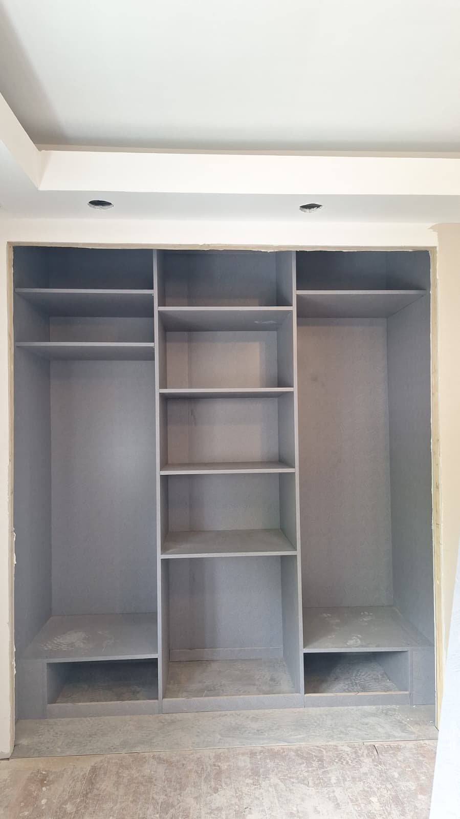 Grey closet interior with central shelves and tall side compartments